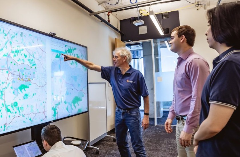 Researchers standing and pointing at a screen